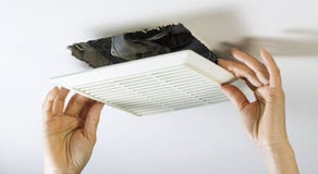 Removing Bathroom Fan Vent Cover to Clean Inside stock photo Removing Bathroom Fan Vent Cover to Clean Inside stock photo