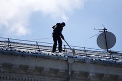 Remoção de neve do telhado da manutenção da casa e do cuidado do telhado no inverno Rússia Berezniki 2 de abril de 2018 fotos de stock Remoção de neve do telhado da manutenção da casa e do cuidado do telhado no inverno Rússia Berezniki 2 de abril de 2018 fotos de stock