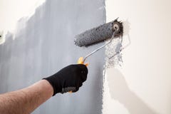 Renovación del interior La mano del hombre sostiene el rodillo de pintura y la pared de la pintura con color gris imágenes de archivo libres de regalías Renovación del interior La mano del hombre sostiene el rodillo de pintura y la pared de la pintura con color gris imágenes de archivo libres de regalías