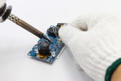 Reparação do técnico eletrônica da placa de circuito por ferros de solda imagens de stock Reparação do técnico eletrônica da placa de circuito por ferros de solda imagens de stock