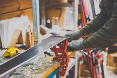 Reparos do tema e manutenção dos esquis O trabalhador masculino está reparando a roupa de trabalho, aplicando a cera na superfíci foto de stock Reparos do tema e manutenção dos esquis O trabalhador masculino está reparando a roupa de trabalho, aplicando a cera na superfíci foto de stock
