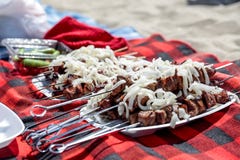 Repas sur une plage : le shashlyk prêt de chiches-kebabs de boeuf a complété à l'oignon blanc image libre de droits Repas sur une plage : le shashlyk prêt de chiches-kebabs de boeuf a complété à l'oignon blanc image libre de droits