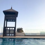 Rescue booth, tower, rescue post on the edge of the water of a luxurious infinity pool merging with the horizon against the backdr stock photos Rescue booth, tower, rescue post on the edge of the water of a luxurious infinity pool merging with the horizon against the backdr stock photos