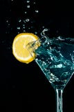Respingo azul da bebida da água do cocktail no vidro com o limão isolado no preto imagens de stock royalty free Respingo azul da bebida da água do cocktail no vidro com o limão isolado no preto imagens de stock royalty free
