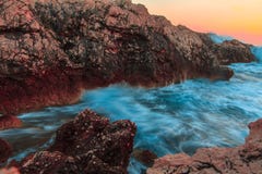 Ressacs faisants rage se cassant sur des roches au coucher du soleil Images stock Ressacs faisants rage se cassant sur des roches au coucher du soleil Images stock