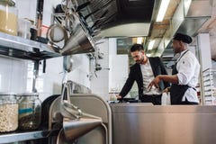 Restauranteigenaar met chef-kok in keuken stock afbeelding Restauranteigenaar met chef-kok in keuken stock afbeelding