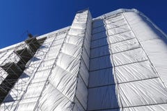 Restauração da construção, a construção coberta com um encerado cinzento fotos de stock Restauração da construção, a construção coberta com um encerado cinzento fotos de stock