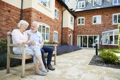 Retired Couple Sitting On Bench With Hot Drink In Assisted Living Facility stock images Retired Couple Sitting On Bench With Hot Drink In Assisted Living Facility stock images