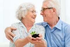 Retirement savings and investements. Elder smiling loving couple holding fresh green sprout, symbol of good bank investement for the retirement royalty free stock images Retirement savings and investements. Elder smiling loving couple holding fresh green sprout, symbol of good bank investement for the retirement royalty free stock images