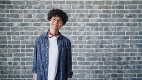 Retrato da jovem mulher alegre que gerencie para a câmera que ri no fundo do tijolo vídeos de arquivo Retrato da jovem mulher alegre que gerencie para a câmera que ri no fundo do tijolo vídeos de arquivo