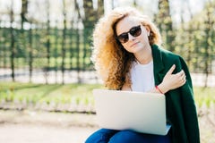Retrato da jovem mulher bonito com os óculos de sol vestindo encaracolado do cabelo louro, o t-shirt branco e o revestimento verd fotografia de stock Retrato da jovem mulher bonito com os óculos de sol vestindo encaracolado do cabelo louro, o t-shirt branco e o revestimento verd fotografia de stock