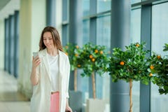 Retrato da jovem mulher com o smartphone no aeroporto internacional Passageiro da linha aérea em uma sala de estar do aeroporto q imagens de stock royalty free Retrato da jovem mulher com o smartphone no aeroporto internacional Passageiro da linha aérea em uma sala de estar do aeroporto q imagens de stock royalty free