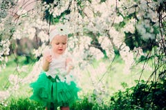 Retrato da mola do bebê bonito na saia verde que aprecia a caminhada exterior no jardim de florescência foto de stock royalty free Retrato da mola do bebê bonito na saia verde que aprecia a caminhada exterior no jardim de florescência foto de stock royalty free