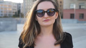 Retrato da mulher de negócios nova nos óculos de sol que anda na rua da cidade Mulher de negócio atrativa que olha a câmera Cara video estoque Retrato da mulher de negócios nova nos óculos de sol que anda na rua da cidade Mulher de negócio atrativa que olha a câmera Cara video estoque