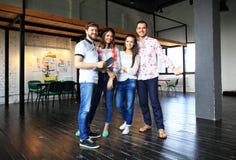 Retrato de jovens felizes em uma reunião que olha a câmera e o sorriso Desenhistas novos que trabalham junto na imagem de stock royalty free Retrato de jovens felizes em uma reunião que olha a câmera e o sorriso Desenhistas novos que trabalham junto na imagem de stock royalty free