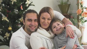 Retrato de la familia alegre que se sienta cerca del árbol de navidad en casa junto Familia joven feliz con el niño metrajes Retrato de la familia alegre que se sienta cerca del árbol de navidad en casa junto Familia joven feliz con el niño metrajes