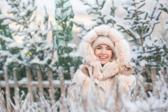 Retrato de la muchacha bonita sonriente en una chaqueta beige en un fondo de las piceas en un invierno fotos de archivo Retrato de la muchacha bonita sonriente en una chaqueta beige en un fondo de las piceas en un invierno fotos de archivo
