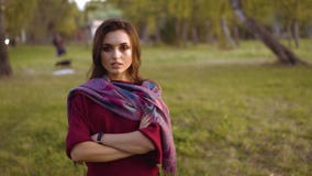 Retrato de la muchacha confiada en manos que cruzan de la bufanda elegante en la cámara en un parque almacen de video Retrato de la muchacha confiada en manos que cruzan de la bufanda elegante en la cámara en un parque almacen de video