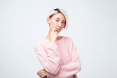 Retrato de la muchacha feliz con el pelo teñido en suéter rosado que piensa mirando la cámara imagenes de archivo Retrato de la muchacha feliz con el pelo teñido en suéter rosado que piensa mirando la cámara imagenes de archivo