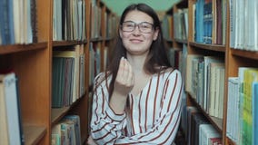 Retrato de la muchacha hermosa joven en biblioteca Estudiante que estudia entre la porción de libros entre los shelfs La muchacha metrajes Retrato de la muchacha hermosa joven en biblioteca Estudiante que estudia entre la porción de libros entre los shelfs La muchacha metrajes