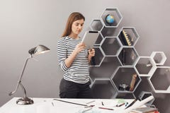Retrato de la muchacha joven alegre hermosa del estudiante del diseñador con el pelo marrón que coloca la tabla cercana, mandando imagenes de archivo Retrato de la muchacha joven alegre hermosa del estudiante del diseñador con el pelo marrón que coloca la tabla cercana, mandando imagenes de archivo