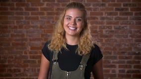 Retrato de la muchacha rubia rizada caucásica hermosa que se coloca al lado de la pared de ladrillo relajada y de la sonrisa metrajes Retrato de la muchacha rubia rizada caucásica hermosa que se coloca al lado de la pared de ladrillo relajada y de la sonrisa metrajes