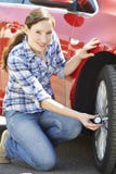 Retrato de la mujer que comprueba la presión de neumático del coche usando el indicador fotos de archivo libres de regalías Retrato de la mujer que comprueba la presión de neumático del coche usando el indicador fotos de archivo libres de regalías