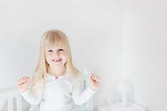 Retrato de la pequeña muchacha linda que se coloca en cama Niño sonriente adorable Niño rubio que aumenta para arriba los puños V fotos de archivo libres de regalías Retrato de la pequeña muchacha linda que se coloca en cama Niño sonriente adorable Niño rubio que aumenta para arriba los puños V fotos de archivo libres de regalías