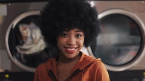 Retrato de la situaci?n afroamericana sonriente joven de la mujer en el lavadero p?blico del autoservicio metrajes Retrato de la situaci?n afroamericana sonriente joven de la mujer en el lavadero p?blico del autoservicio metrajes