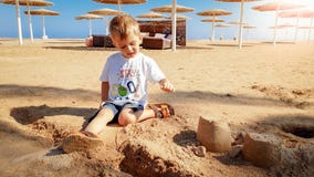 Retrato de los 3 a?os lindos del ni?o peque?o que se sienta en la playa arenosa y que juega con los juguetes y el castillo constr imagenes de archivo Retrato de los 3 a?os lindos del ni?o peque?o que se sienta en la playa arenosa y que juega con los juguetes y el castillo constr imagenes de archivo