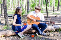 Retrato de pares felizes loving novos com a guitarra na floresta imagem de stock royalty free Retrato de pares felizes loving novos com a guitarra na floresta imagem de stock royalty free