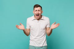 Retrato de rir o homem novo smirked na roupa ocasional que está, mãos de espalhamento isoladas na parede azul de turquesa fotografia de stock Retrato de rir o homem novo smirked na roupa ocasional que está, mãos de espalhamento isoladas na parede azul de turquesa fotografia de stock