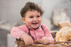 Retrato de um bebê bonito dentro de uma cesta com pão na padaria fotografia de stock Retrato de um bebê bonito dentro de uma cesta com pão na padaria fotografia de stock