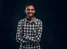 Retrato de um indivíduo indiano de sorriso que veste uma camisa quadriculado que levanta com seus braços cruzados e que olha a câ fotos de stock royalty free Retrato de um indivíduo indiano de sorriso que veste uma camisa quadriculado que levanta com seus braços cruzados e que olha a câ fotos de stock royalty free