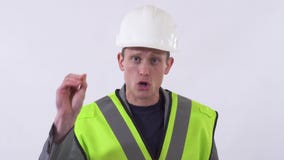 Retrato de um indivíduo seguro em um uniforme do construtor e do capacete branco em sua cabeça que fala à câmera que dá o conselh video estoque Retrato de um indivíduo seguro em um uniforme do construtor e do capacete branco em sua cabeça que fala à câmera que dá o conselh video estoque