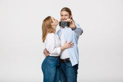 Retrato de um par feliz que faz a foto do selfie com o smartphone sobre o fundo branco do estúdio imagens de stock Retrato de um par feliz que faz a foto do selfie com o smartphone sobre o fundo branco do estúdio imagens de stock
