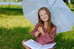 Retrato de uma menina bonita no vestido de Borgonha a criança sorri e lê o livro no parque imagem de stock Retrato de uma menina bonita no vestido de Borgonha a criança sorri e lê o livro no parque imagem de stock