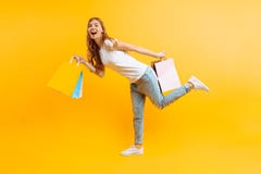 Retrato de uma moça entusiástica com os sacos nas mãos, menina feliz após a compra no fundo amarelo imagens de stock Retrato de uma moça entusiástica com os sacos nas mãos, menina feliz após a compra no fundo amarelo imagens de stock