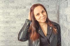 Retrato de uma moça sem composição em sua cara em um revestimento preto contra uma parede de tijolo cinzenta foto de stock royalty free Retrato de uma moça sem composição em sua cara em um revestimento preto contra uma parede de tijolo cinzenta foto de stock royalty free