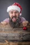 Retrato de un hombre barbudo divertido con el casquillo de santa que lleva a cabo un diciembre rojo Fotografía de archivo libre de regalías Retrato de un hombre barbudo divertido con el casquillo de santa que lleva a cabo un diciembre rojo Fotografía de archivo libre de regalías