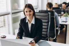 Retrato de una empresaria feliz que se sienta en su lugar de trabajo en oficina fotografía de archivo Retrato de una empresaria feliz que se sienta en su lugar de trabajo en oficina fotografía de archivo