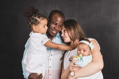 Retrato de una familia internacional con dos niños en un fondo negro de la pared fotografía de archivo libre de regalías Retrato de una familia internacional con dos niños en un fondo negro de la pared fotografía de archivo libre de regalías