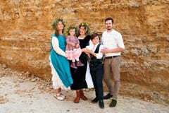 Retrato de una familia de tres generaciones en ropa y guirnaldas retras rústicas del vintage contra un fondo de la pared de la ar fotografía de archivo Retrato de una familia de tres generaciones en ropa y guirnaldas retras rústicas del vintage contra un fondo de la pared de la ar fotografía de archivo