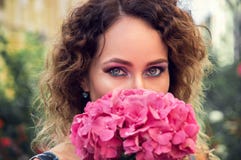 Retrato de una mujer joven que huele una hortensia rosada grande Mirada misteriosa enviada a la cámara fotografía de archivo libre de regalías Retrato de una mujer joven que huele una hortensia rosada grande Mirada misteriosa enviada a la cámara fotografía de archivo libre de regalías