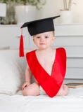 Retrato del bebé adorable en el sombrero del birrete y la cinta roja que miran in camera Concepto de educación temprana del niño foto de archivo Retrato del bebé adorable en el sombrero del birrete y la cinta roja que miran in camera Concepto de educación temprana del niño foto de archivo