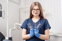 Retrato del dentista atractivo de sexo femenino joven que celebra las herramientas dentales - en la oficina dental del morden fotografía de archivo libre de regalías Retrato del dentista atractivo de sexo femenino joven que celebra las herramientas dentales - en la oficina dental del morden fotografía de archivo libre de regalías