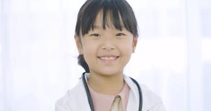 Retrato del doctor joven de la niña en la capa blanca con el estetoscopio que mira en la cámara metrajes Retrato del doctor joven de la niña en la capa blanca con el estetoscopio que mira en la cámara metrajes