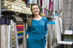 Retrato del dueño maduro feliz de la mujer en la tienda interior de las telas, muestras de la tela del fondo Tienda de la materia imagen de archivo Retrato del dueño maduro feliz de la mujer en la tienda interior de las telas, muestras de la tela del fondo Tienda de la materia imagen de archivo