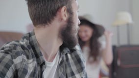 Retrato del hombre barbudo ofendido triste en las vueltas y las miradas del primero plano en su esposa feliz que intenta en un so almacen de metraje de vídeo Retrato del hombre barbudo ofendido triste en las vueltas y las miradas del primero plano en su esposa feliz que intenta en un so almacen de metraje de vídeo
