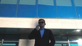 Retrato del hombre de negocios joven en gafas de sol que habla en el teléfono al aire libre cerca de oficina Ciérrese para arriba metrajes Retrato del hombre de negocios joven en gafas de sol que habla en el teléfono al aire libre cerca de oficina Ciérrese para arriba metrajes